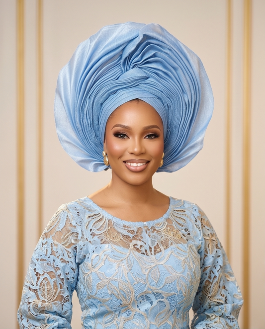A woman wearing a light blue lace dress with a matching pleated blue headwrap and gold earrings, set against a beige background with vertical gold-toned lines.
